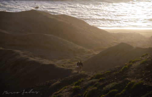 People walk down the hills at sunset.